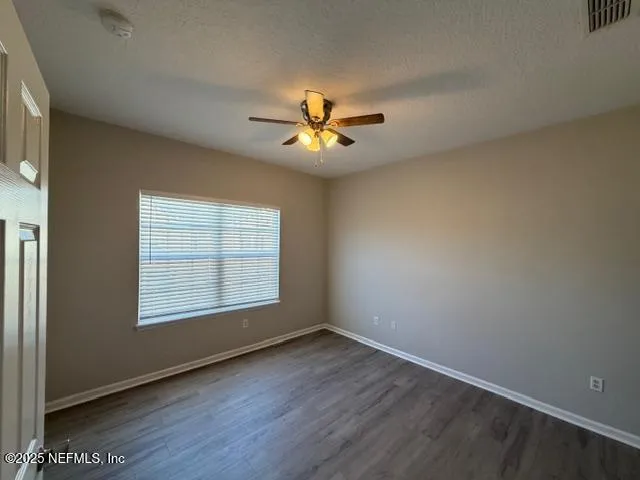 an empty room with windows and chandelier fan