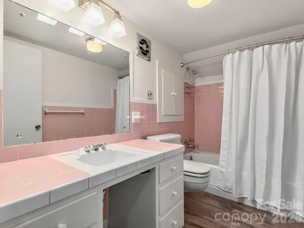 a bathroom with a sink a toilet a mirror and shower