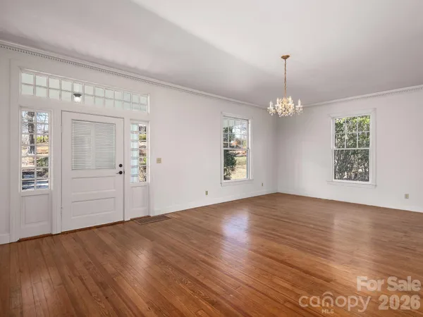 an empty room with wooden floor mirror and windows