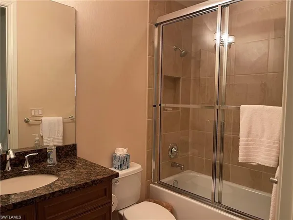 a bathroom with a granite countertop sink toilet and shower