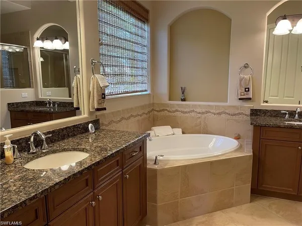 a bathroom with a granite countertop sink a mirror and a bathtub