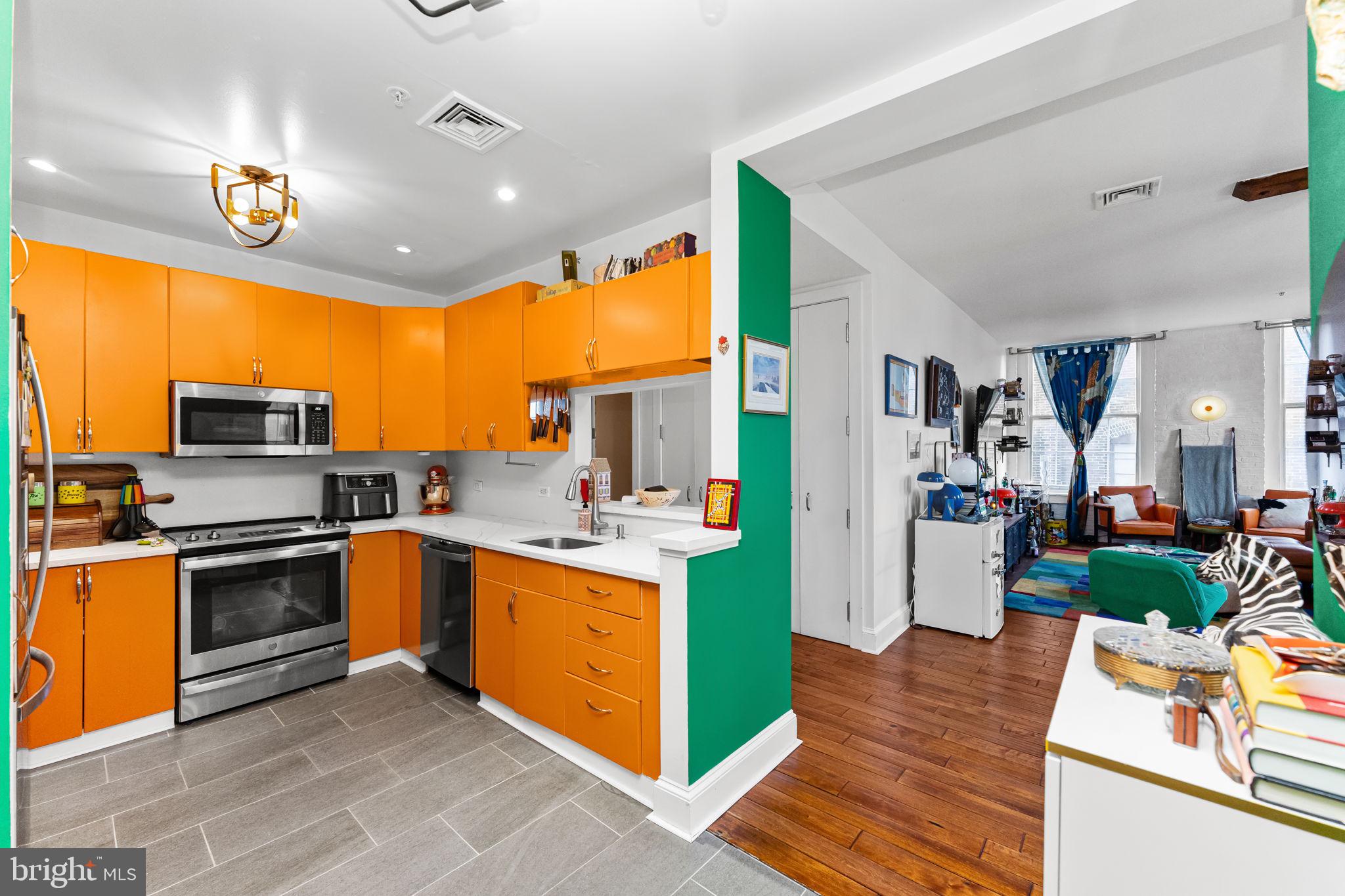 214 New Street, Unit G Philadelphia, PA 19106 - Photo 5 of 17 a kitchen with stainless steel appliances kitchen island granite countertop a stove top oven a sink dishwasher and cabinets with wooden floor