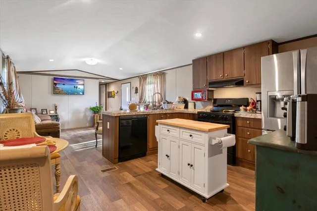 a kitchen with stainless steel appliances granite countertop a stove top oven a refrigerator a sink and dishwasher with white cabinets