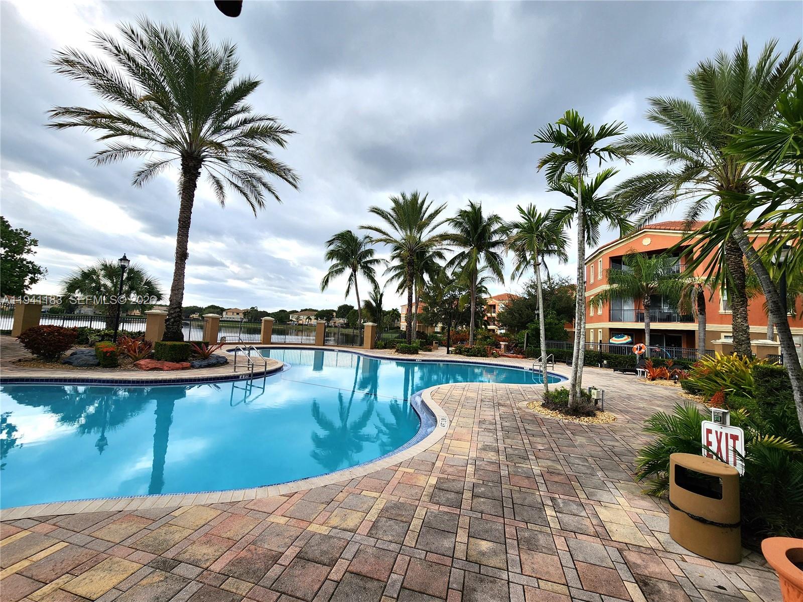 4602 Southwest 160th Avenue, Unit 524 Miramar, FL 33027 - Photo 27 of 33 a view of a swimming pool with a lounge chair and palm trees