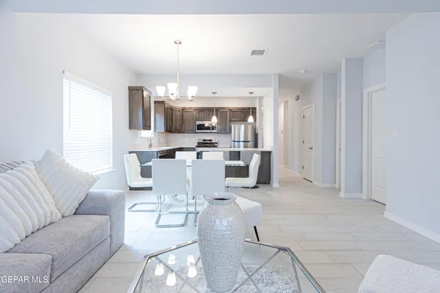 a kitchen with kitchen island a dining table chairs and a refrigerator