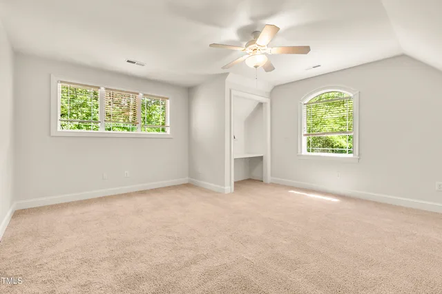 an empty room with windows and chandelier fan