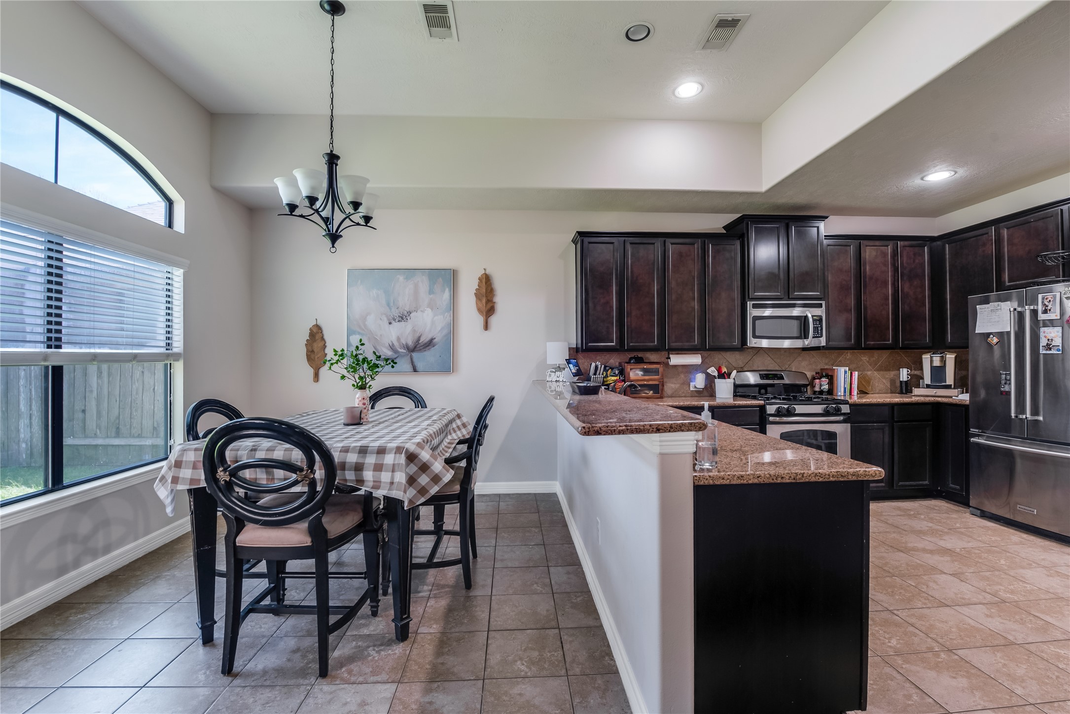 25118 Andris Lane Spring, TX 77386 - Photo 15 of 42 a kitchen with granite countertop stainless steel appliances a table chairs refrigerator and microwave