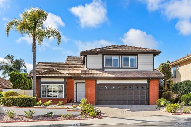 a front view of a house with yard and parking