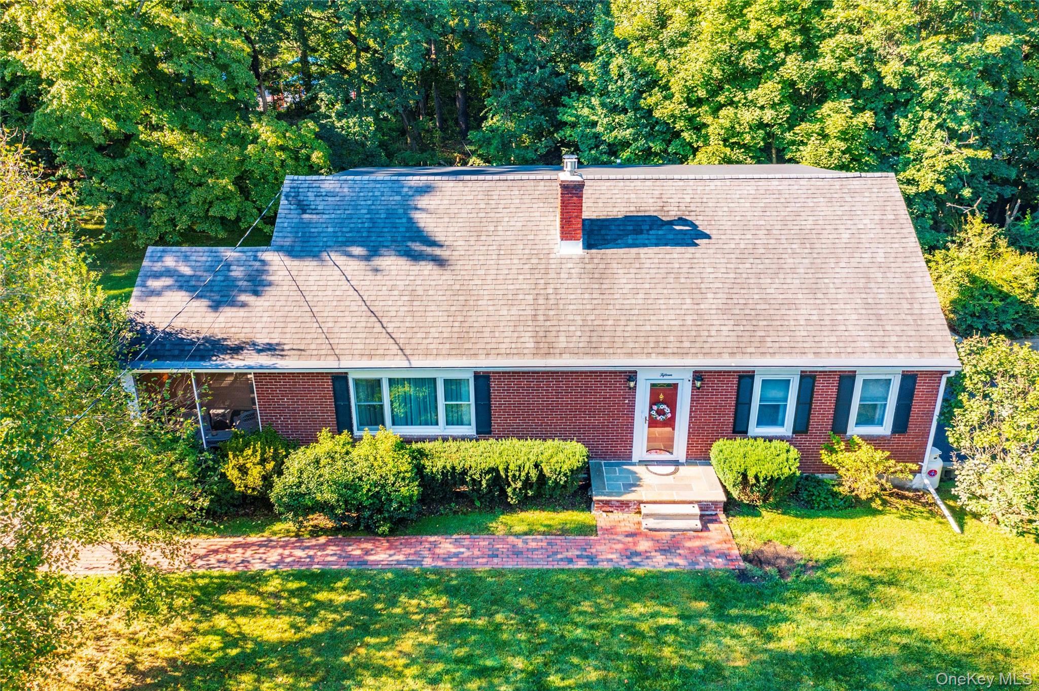 View of front of house with a chimney, a front yard, and brick siding