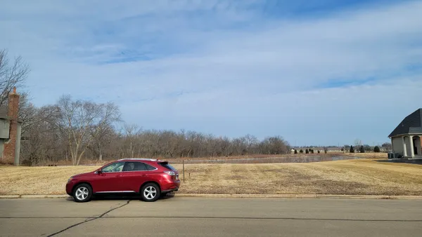 a red car parked in the river next to a lake