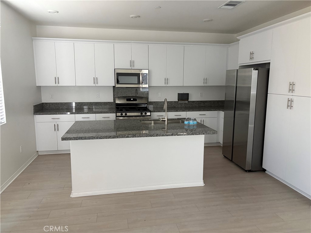 2544 Gunner Ridge Way Rialto, CA 92377 - Photo 22 of 22 a kitchen with stainless steel appliances granite countertop a stove a refrigerator a sink a microwave and island