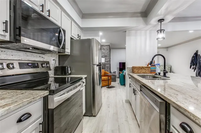 a kitchen with stainless steel appliances granite countertop a table chairs sink and cabinets
