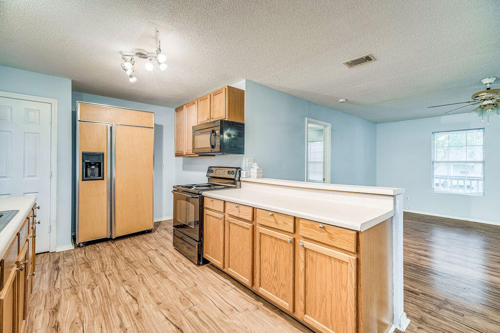 1003 Pinetree Road Mary Esther, FL 32569 - Photo 12 of 29 a large kitchen with stainless steel appliances granite countertop a refrigerator a sink dishwasher a stove with wooden cabinets and floor