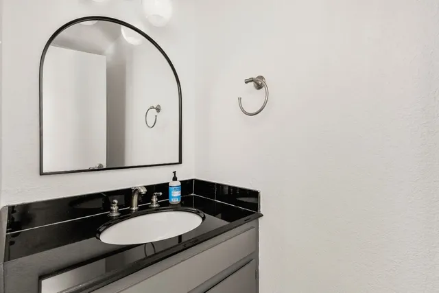 a bathroom with a granite countertop sink and a mirror