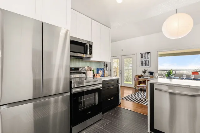 a kitchen with stainless steel appliances granite countertop a refrigerator a stove top oven a sink dishwasher and white cabinets with wooden floor