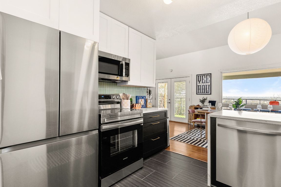 3306 Hyclimb Circle, Unit A Austin, TX 78723 - Photo 7 of 26 a kitchen with stainless steel appliances granite countertop a refrigerator a stove top oven a sink dishwasher and white cabinets with wooden floor