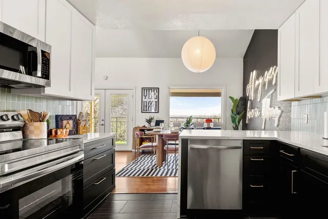 a kitchen with stainless steel appliances granite countertop a stove top oven a sink dishwasher and white cabinets with wooden floor