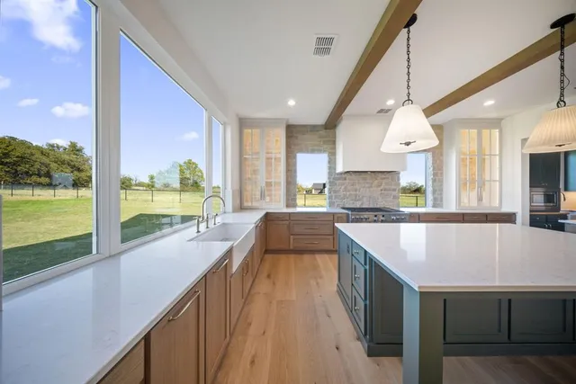 a large kitchen with kitchen island a large window and a sink