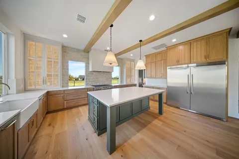 a large kitchen with kitchen island granite countertop a large window a sink and stainless steel appliances