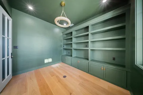 a view of an empty room with wooden floor and a fireplace
