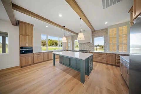 a large kitchen with a large counter top space a sink stainless steel appliances and windows