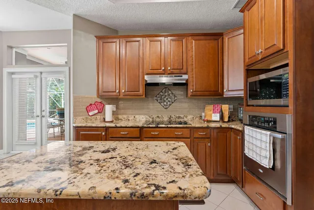 a kitchen with granite countertop wooden cabinets and a stove