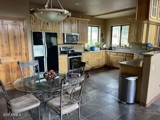 a kitchen with stainless steel appliances kitchen island granite countertop a stove a sink a dining table and chairs