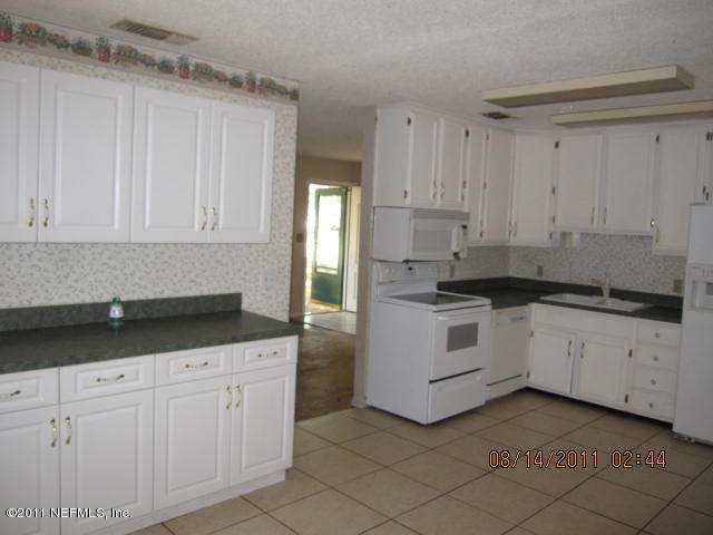 1360 Prince Road St. Augustine, FL 32086 - Photo 3 of 8 a kitchen with granite countertop white cabinets and stainless steel appliances
