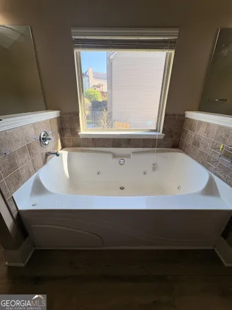 a spacious bathroom with a tub double sink and a mirror
