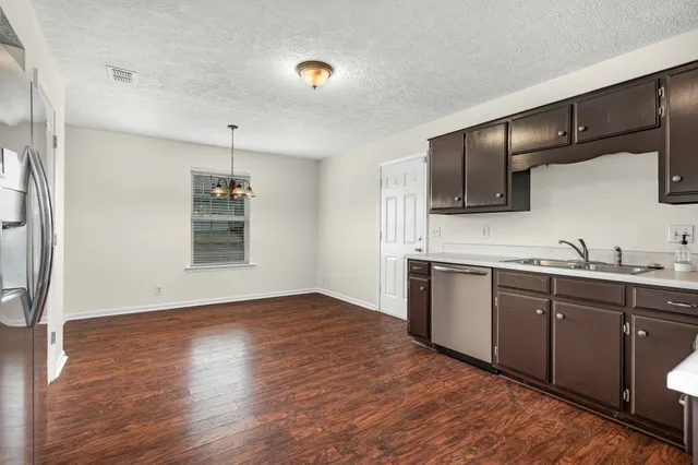 a kitchen with granite countertop stainless steel appliances a sink cabinets and wooden floor