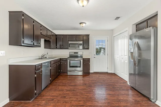 a kitchen with stainless steel appliances granite countertop a refrigerator a stove top oven a sink and dishwasher