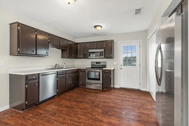 a kitchen with stainless steel appliances granite countertop a refrigerator stove and sink
