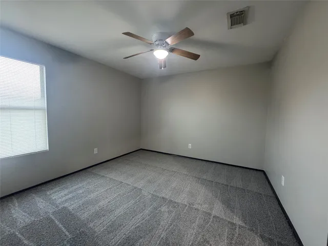 an empty room with a ceiling fan and window