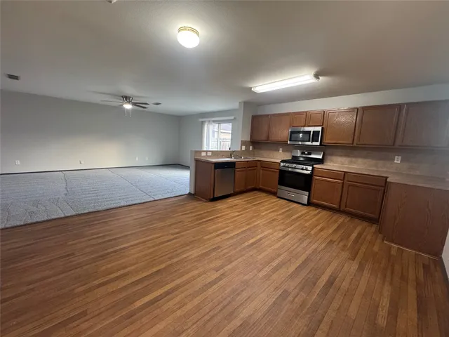 a kitchen with stainless steel appliances granite countertop a sink dishwasher stove and wooden floor