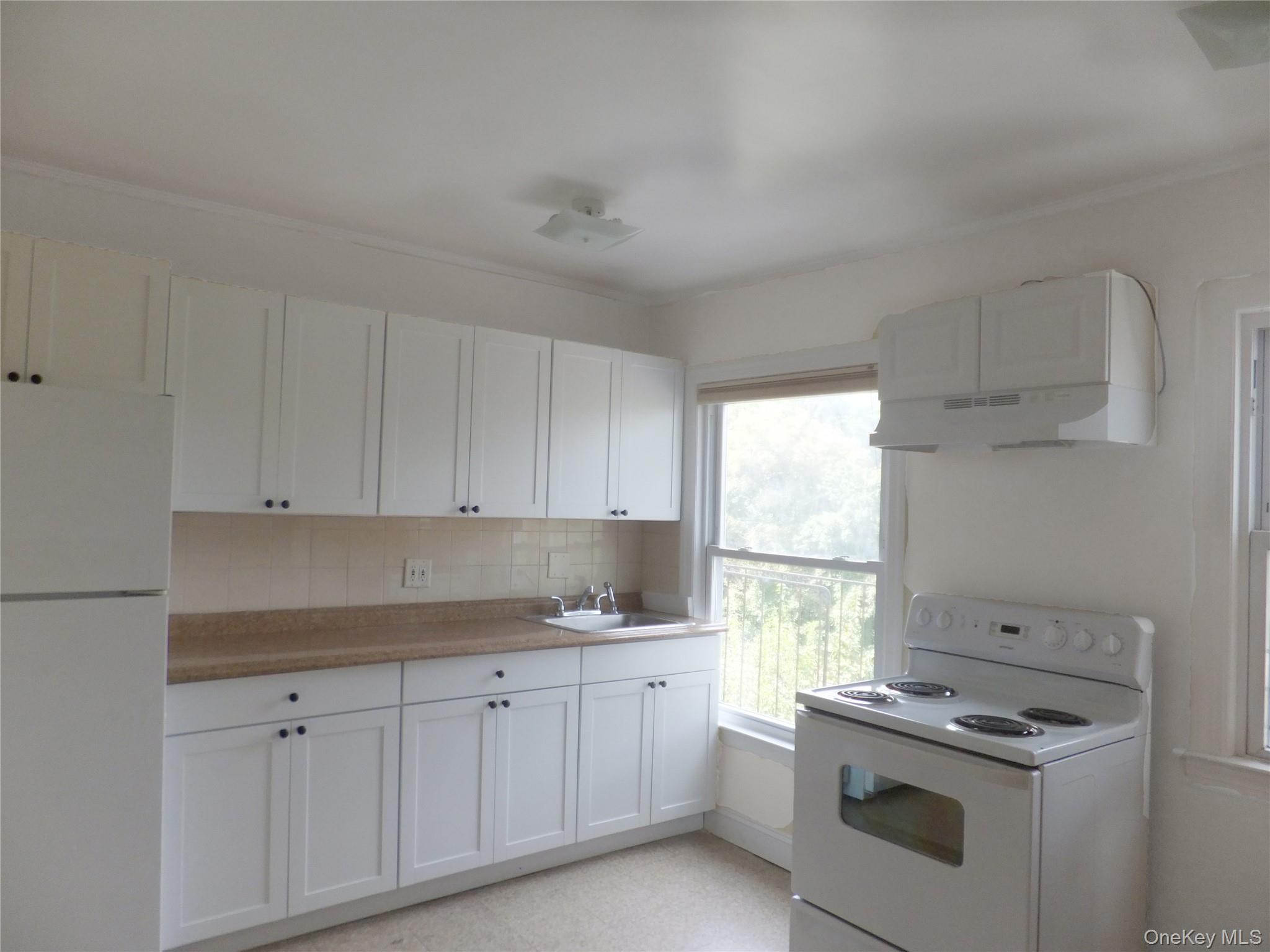 107 Kensington Road, Unit 5 Bronxville, NY 10708 - Photo 3 of 17 Kitchen with white appliances, light countertops, white cabinets, under cabinet range hood, and tasteful backsplash