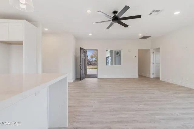a view of a livingroom with a ceiling fan & kitchen view