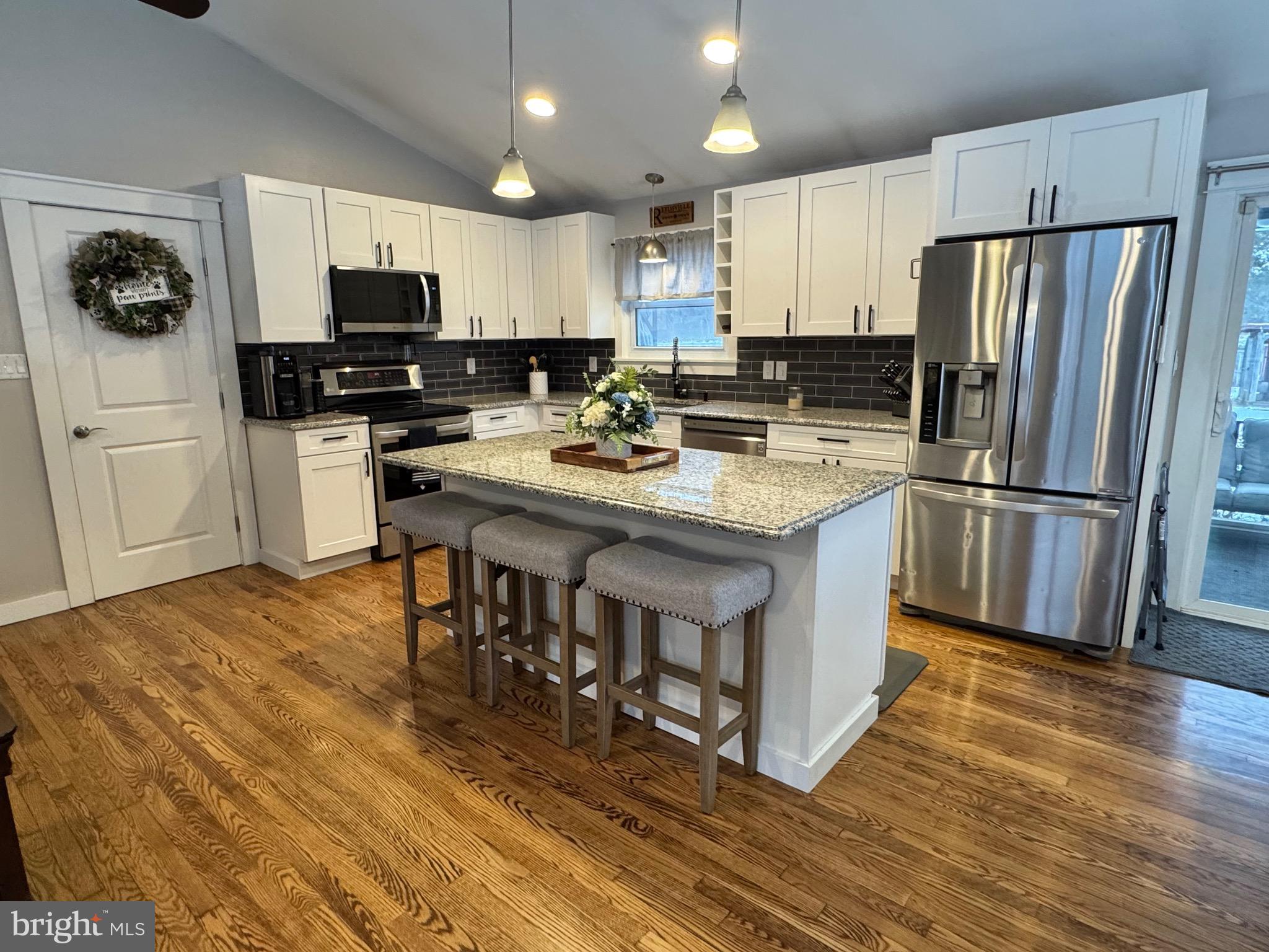699 Honey Creek Road Reedsville, PA 17084 - Photo 5 of 26 a kitchen with stainless steel appliances a stove a sink a refrigerator and white cabinets with wooden floor
