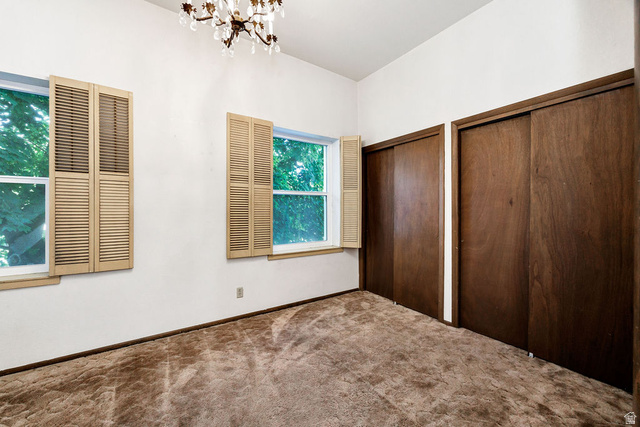 299 West Center Street, Unit 2 Logan, UT 84321 - Photo 21 of 46 Bright room featuring two windows with louvered shutters, a crystal chandelier, and two spacious sliding-door closets with wood-finish doors