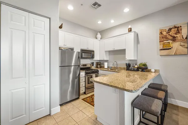 a kitchen with stainless steel appliances granite countertop a refrigerator a stove and a sink