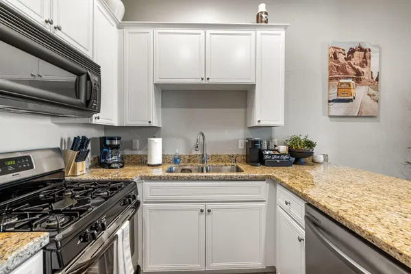 a kitchen with granite countertop a sink a stove and cabinets