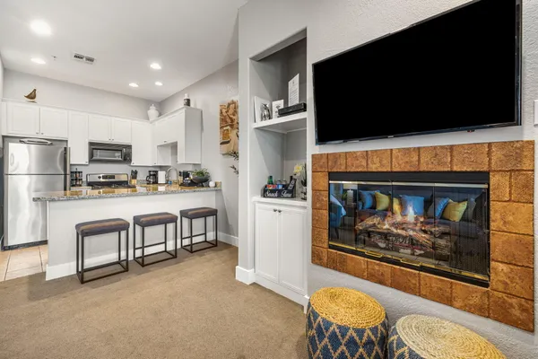 a living room with stainless steel appliances furniture a fireplace a flat screen tv and view kitchen
