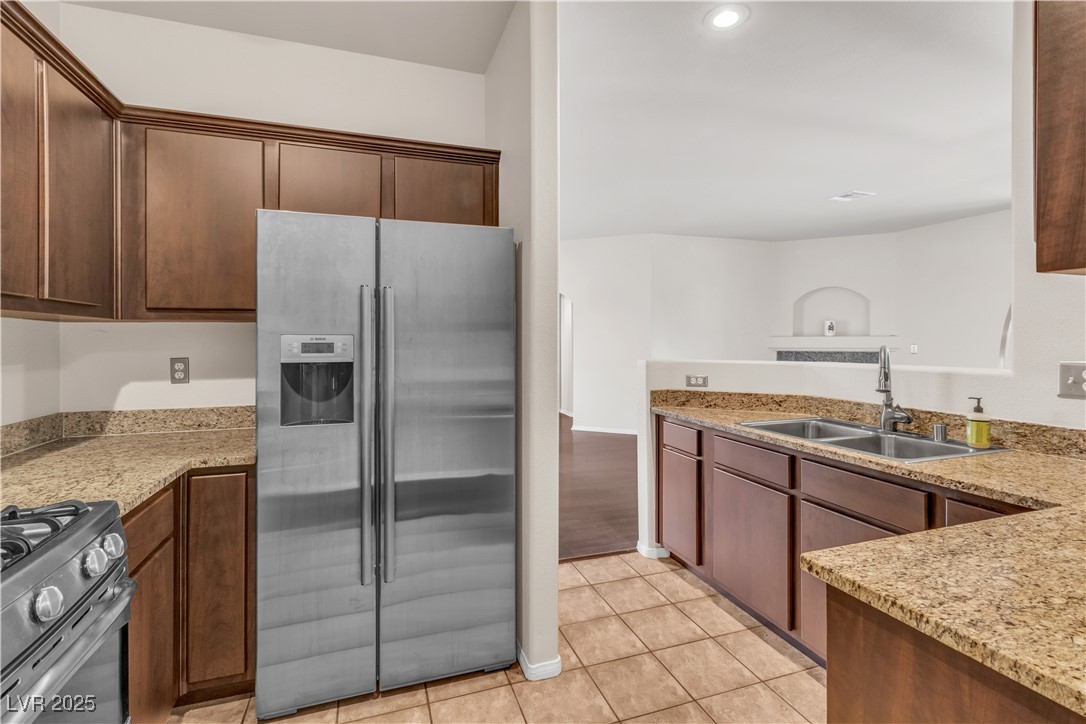 2050 West Warm Springs Road, Unit 1822 Henderson, NV 89014 - Photo 3 of 55 Kitchen with light stone countertops, light tile patterned floors, a new sink, and high end appliances with stainless steel finishes and new cabinets.