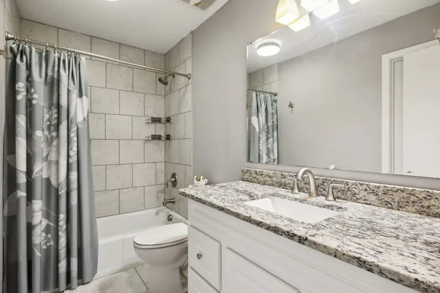 a bathroom with a granite countertop sink toilet and shower