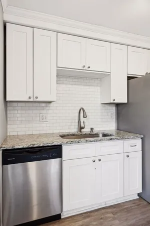 a kitchen with granite countertop white cabinets and a sink