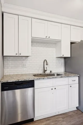 a kitchen with granite countertop white cabinets and a sink
