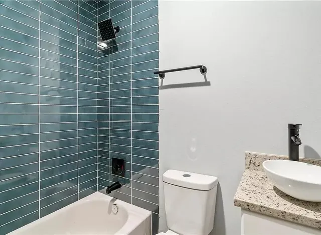a bathroom with a granite countertop toilet a sink and mirror