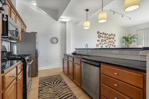 a kitchen with granite countertop a refrigerator a stove a sink a dining table and chairs with wooden floor