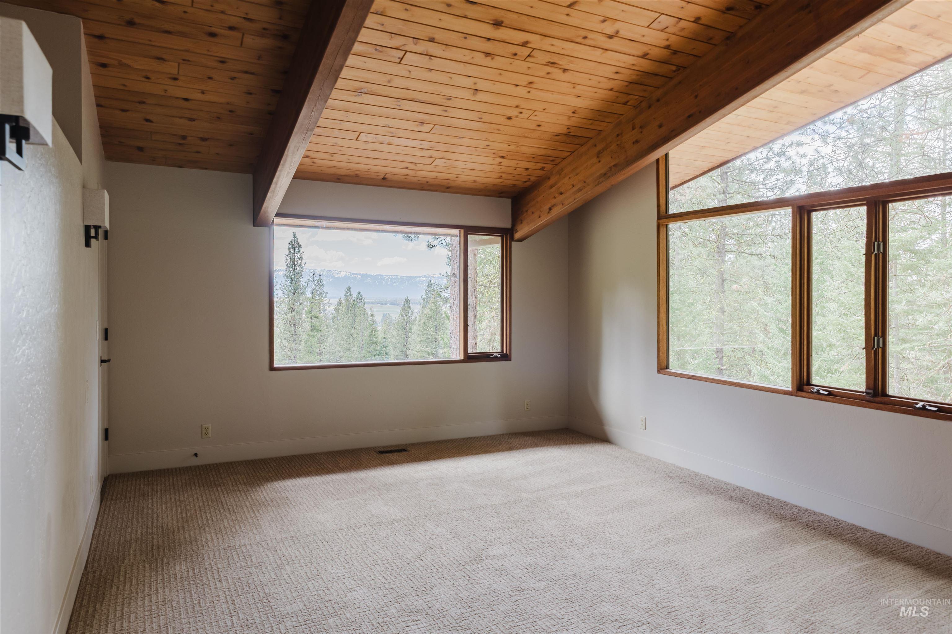136 Silver Fox Trail McCall, ID 83638 - Photo 21 of 31 Room featuring a wood-panel vaulted ceiling with exposed beams, wood-frame windows, and wall-mounted sconces