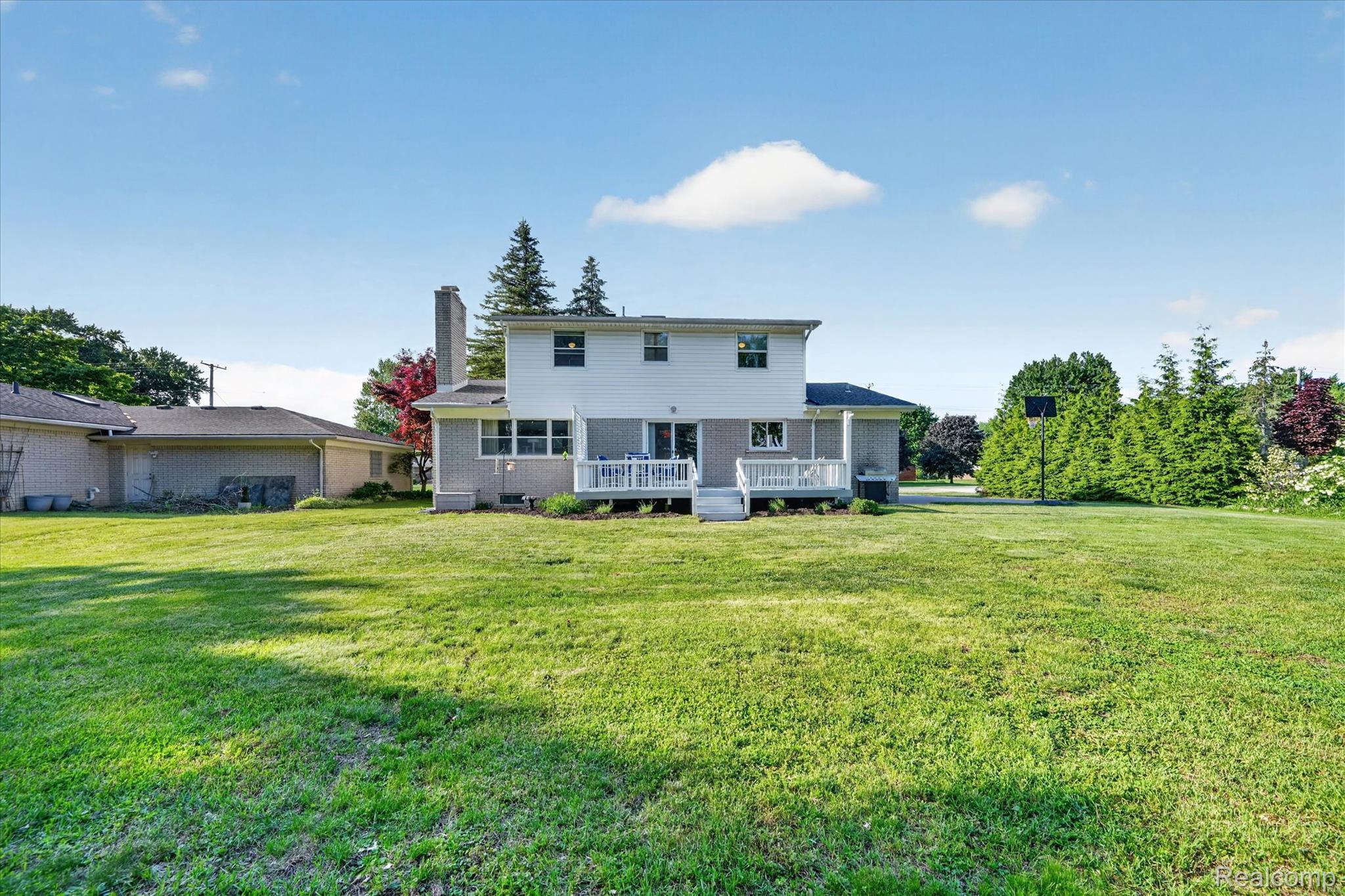 18178 22 Mile Road Macomb, MI 48044 - Photo 40 of 43 Expansive green lawn surrounds the two-story residence featuring a white deck with railings and a partial brick exterior