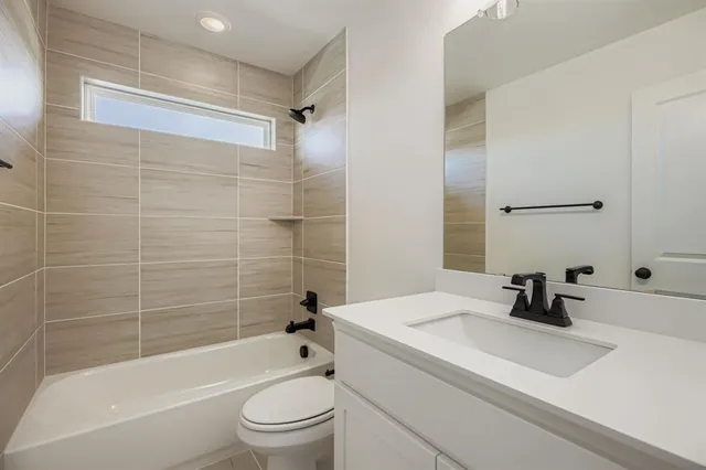 a bathroom with a bathtub shower sink vanity mirror and toilet
